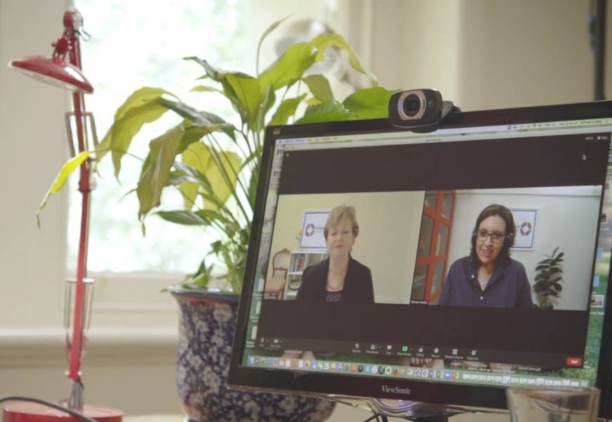 Monitor with web camera on desk with a lamp showing Simone Dudley from Therapy Connect on a video call